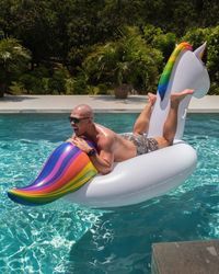 Shirtless man lying on raft in swimming pool