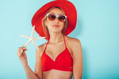 Portrait of woman wearing sunglasses while standing against blue background