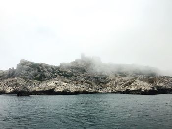 Scenic view of sea by mountains against sky