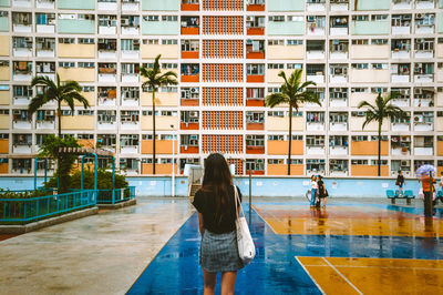 Rear view of woman standing against buildings in city