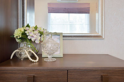 Flower vase on table by window at home