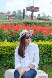 Beautiful woman wearing sunglasses while sitting against plants