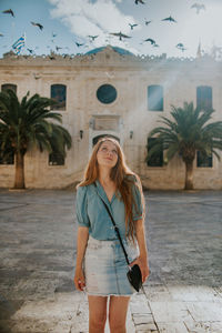 Portrait of beautiful young woman standing against building