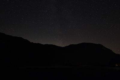 Scenic view of silhouette mountains against star field at night