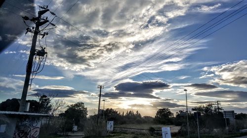 Low angle view of electricity pylon against sky during sunset