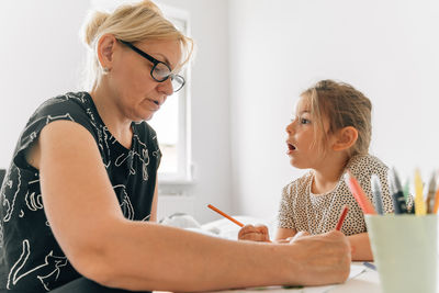 Grandmother helping granddaughter in studying at home