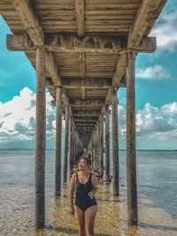 Woman in swimsuit standing under bridge