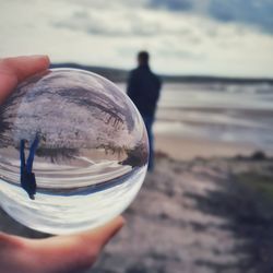 Midsection of person holding crystal ball on beach