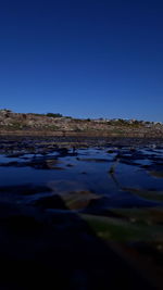 Surface level of land against clear blue sky