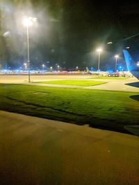 Illuminated street light on field against sky at night