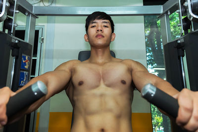 Portrait of shirtless man exercising at gym