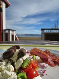 Greek salad in plate on table against cloudy sky during sunny day