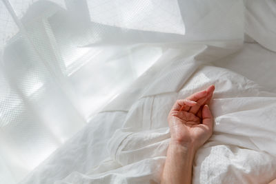 Cropped hand of person on bed