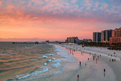 People on beach against sky during sunset