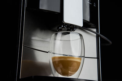 Coffee machine dispensing fresh brew into cup against dark background