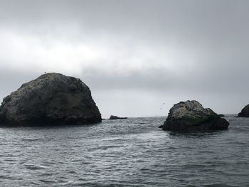 Rock formation in sea against sky