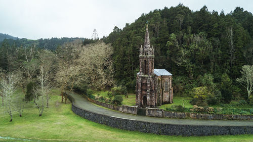 Stone wall amidst trees and buildings against sky