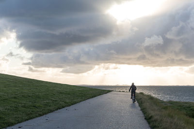 Rear view of man walking on road against sky