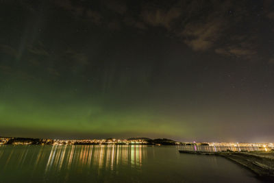 Aurora over  city night sky with water reflections