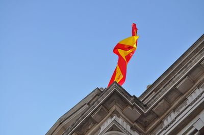 Low angle view of spanish flag on historic building against clear sky