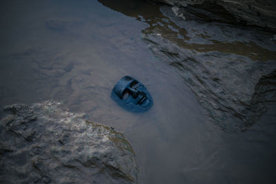 Selective focus the black plastic mask is placed in the rocky river water. and evil mask with drama