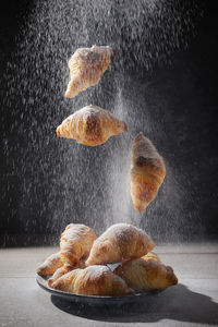 Closeup fresh mini croissants and sugar powder on wooden table