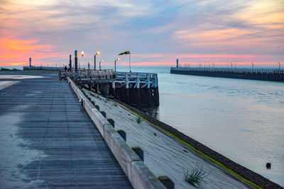 Pier over sea against sky during sunset