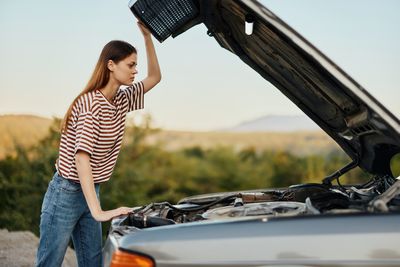 Side view of young woman holding car