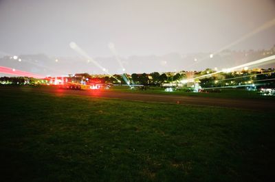 Illuminated grass against sky at night