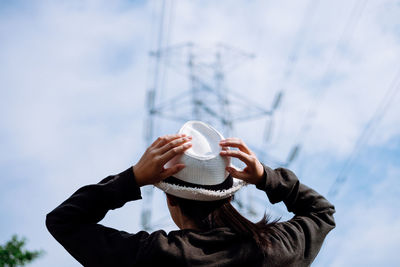 Close-up of woman holding hat against sky