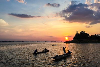 Boats sailing in sea against sky at sunset