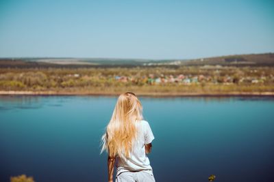 Rear view of woman standing against blue sky