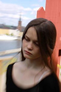 Close-up of young woman in city against sky