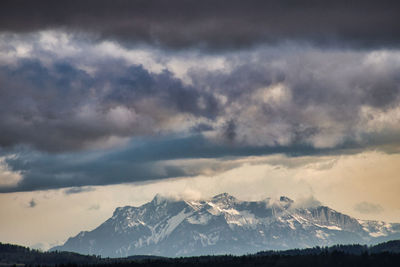 Scenic view of snowcapped mountain against cloudy sky during sunset