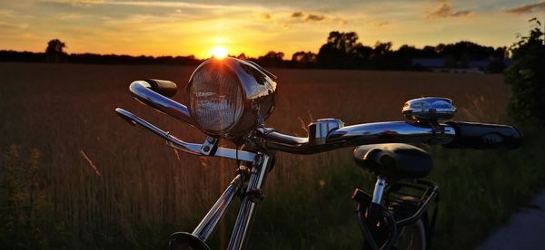 Bicycles on field against sky during sunset