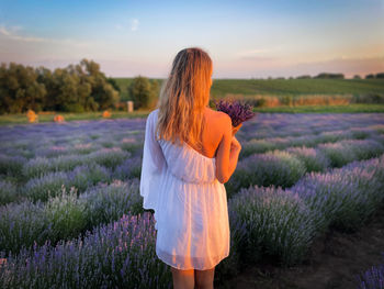 Rear view of woman standing on field against sky