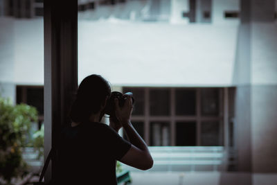 Rear view of woman photographing through smart phone