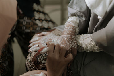 Cropped image of woman applying henna tattoo on bride hands