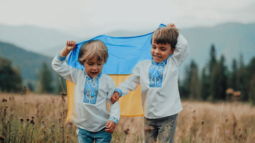 Portrait of siblings standing on field