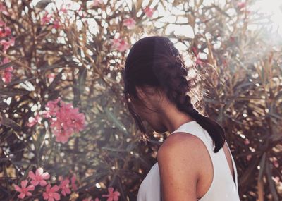 Side view of young woman standing against plants at park