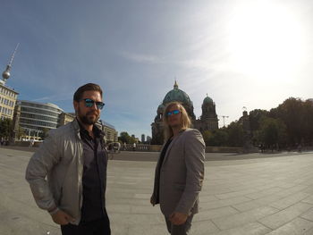 Male friends standing on street against berlin cathedral in city