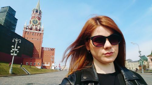 Portrait of beautiful woman in city against sky