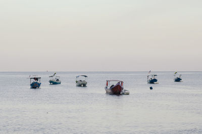 Boats in sea against clear sky