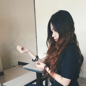 Side view of thoughtful woman with long hair wearing bracelet standing in classroom