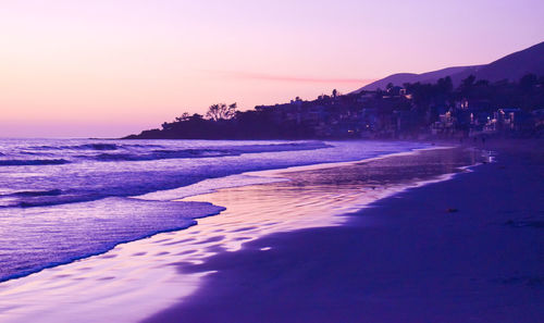 Scenic view of beach against clear sky at sunset