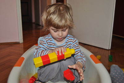 Cute boy sitting while playing with blocks at home