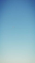 Low angle view of airplane flying against clear blue sky