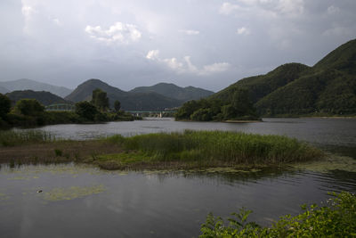 Scenic view of lake by mountains against sky