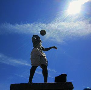 Low angle view of woman against blue sky