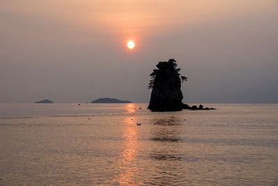 Silhouette stack rock in sea against sky during sunset